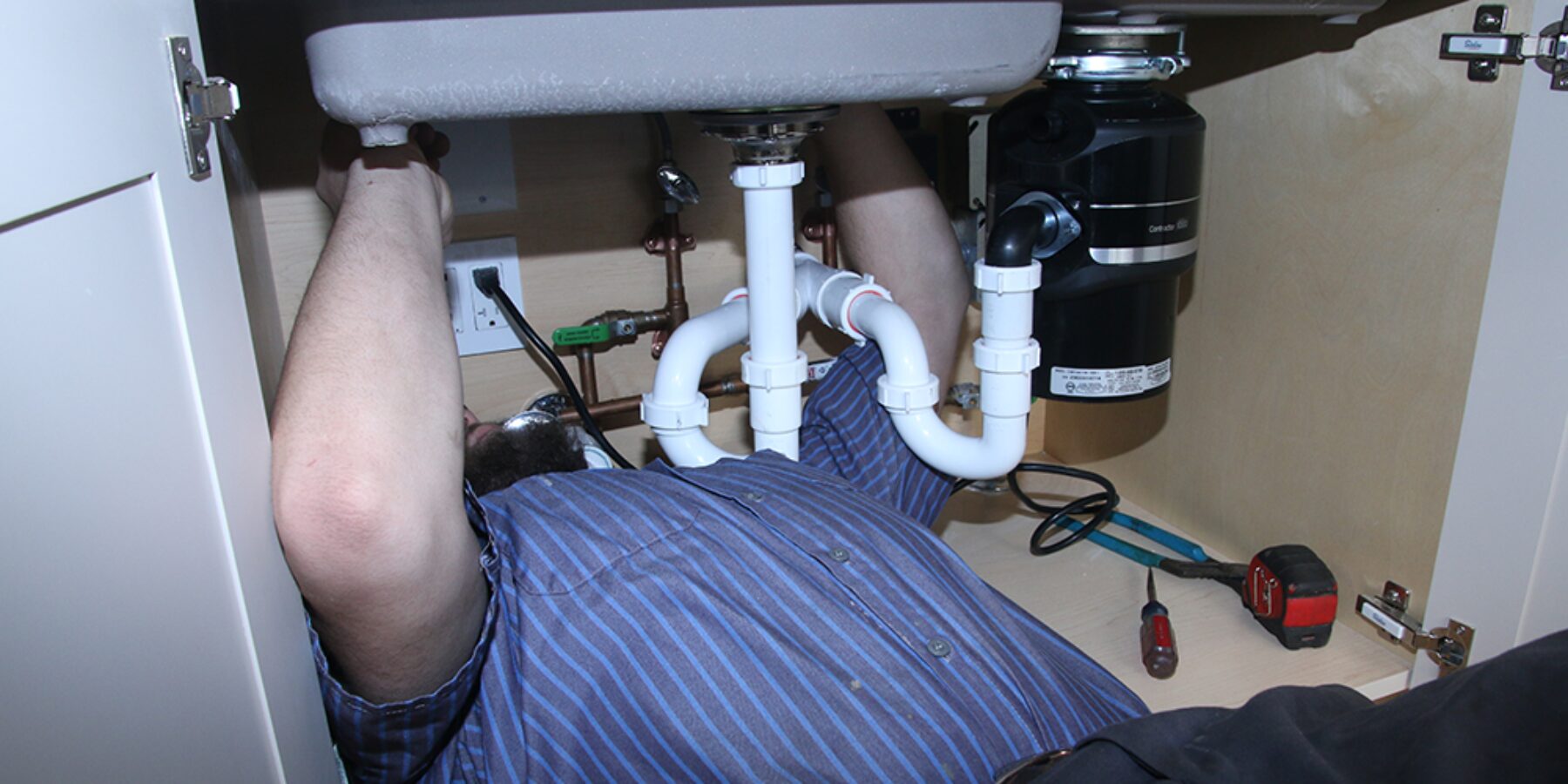 Plumber cleaning a kitchen drain